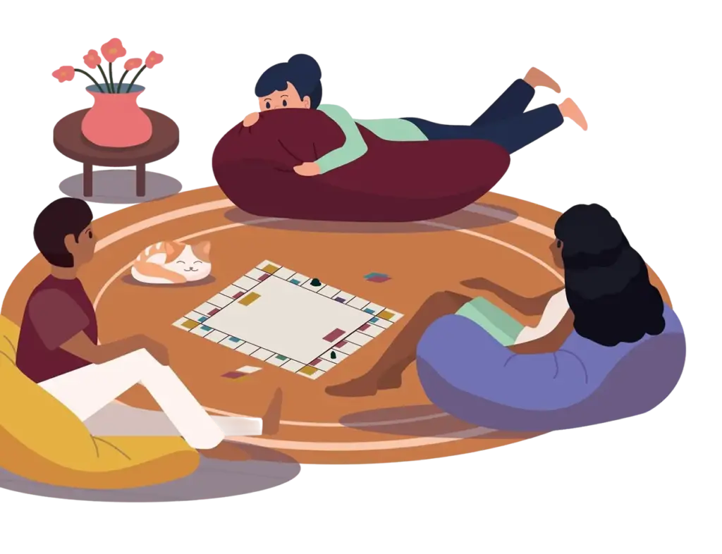 Três amigos sentados confortavelmente num tapete a jogar um jogo de tabuleiro; ao lado deles, um gato está a dormir e na mesa de apoio há um vaso com flores.
